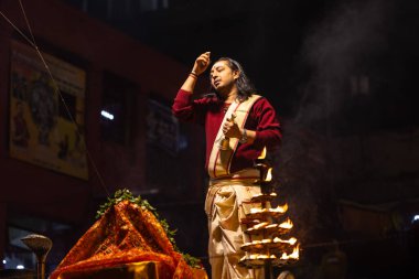 Varanasi, Uttar Pradesh, Hindistan - 20 Ocak 2024: Ganga aarti, Geleneksel elbise içinde Dashashwamedh ghat kutsal nehir keneviri akşam ayini yapan kimliği belirsiz genç bir erkek rahibin portresi.