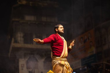 Varanasi, Uttar Pradesh, Hindistan - 20 Ocak 2024: Ganga aarti, Geleneksel elbise içinde Dashashwamedh ghat kutsal nehir keneviri akşam ayini yapan kimliği belirsiz genç bir erkek rahibin portresi.