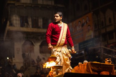 Varanasi, Uttar Pradesh, Hindistan - 20 Ocak 2024: Ganga aarti, Geleneksel elbise içinde Dashashwamedh ghat kutsal nehir keneviri akşam ayini yapan kimliği belirsiz genç bir erkek rahibin portresi.