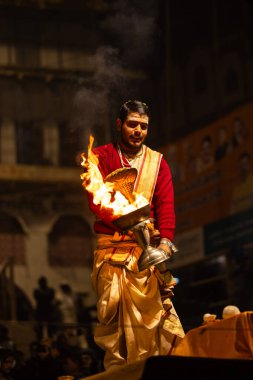 Varanasi, Uttar Pradesh, Hindistan - 20 Ocak 2024: Ganga aarti, Geleneksel elbise içinde Dashashwamedh ghat kutsal nehir keneviri akşam ayini yapan kimliği belirsiz genç bir erkek rahibin portresi.