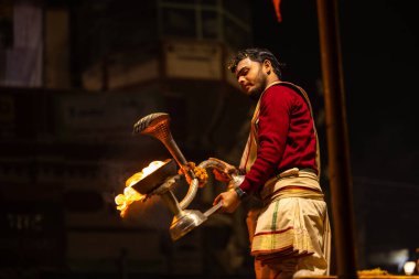 Varanasi, Uttar Pradesh, Hindistan - 20 Ocak 2024: Ganga aarti, Geleneksel elbise içinde Dashashwamedh ghat kutsal nehir keneviri akşam ayini yapan kimliği belirsiz genç bir erkek rahibin portresi.