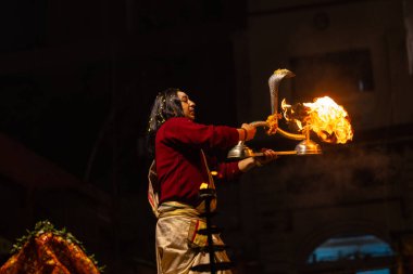 Varanasi, Uttar Pradesh, Hindistan - 20 Ocak 2024: Ganga aarti, Geleneksel elbise içinde Dashashwamedh ghat kutsal nehir keneviri akşam ayini yapan kimliği belirsiz genç bir erkek rahibin portresi.