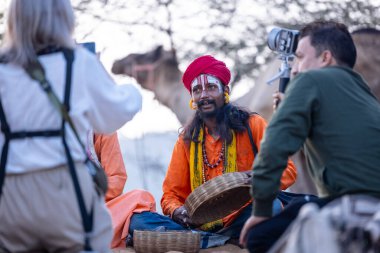 Puşkar, Rajasthan, Hindistan - 10 Kasım 2024: Geleneksel beyaz giysili rajasthani erkek portresi çöl panayırında renkli türbanlı deve fuarı sırasında develeri takas etmek için.