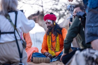 Puşkar, Rajasthan, Hindistan - 10 Kasım 2024: Geleneksel beyaz giysili rajasthani erkek portresi çöl panayırında renkli türbanlı deve fuarı sırasında develeri takas etmek için.