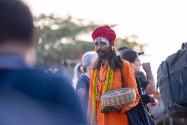 Puşkar, Rajasthan, Hindistan - 10 Kasım 2024: Geleneksel beyaz giysili rajasthani erkek portresi çöl panayırında renkli türbanlı deve fuarı sırasında develeri takas etmek için.