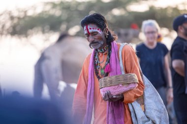 Puşkar, Rajasthan, Hindistan - 10 Kasım 2024: Geleneksel beyaz giysili rajasthani erkek portresi çöl panayırında renkli türbanlı deve fuarı sırasında develeri takas etmek için.