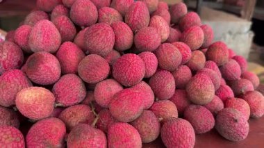 Masanın üstünde taze kırmızı liçi meyvesi var. 