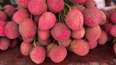 Masanın üstünde taze kırmızı liçi meyvesi var. 