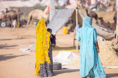Puşkar, Rajasthan, Hindistan - 10 Kasım 2024: Pushkar Deve Fuarı sahasında, kimliği belirsiz, geleneksel renkli elbiseli Hintli bir kadının portresi.