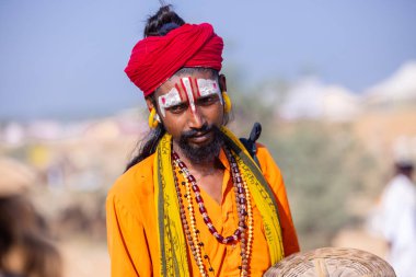 Pushkar, Rajasthan, India - November 10, 2024: Portrait of a young snake charmer male with colorful turban at fair ground during pushkar camel fair.