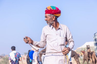 Puşkar, Rajasthan, Hindistan - 10 Kasım 2024: Deve ticareti sırasında geleneksel beyaz giysili rajasthani erkek portresi.