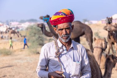 Puşkar, Rajasthan, Hindistan - 10 Kasım 2024: Deve ticareti sırasında geleneksel beyaz giysili rajasthani erkek portresi.