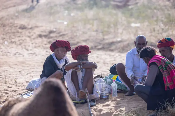 Puşkar, Rajasthan, Hindistan - 10 Kasım 2024: Geleneksel giysili rajasthani erkek portresi çöl panayırında renkli türbanlarla deve pazarında deve ticareti yaparken.