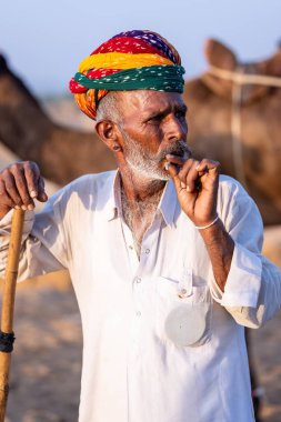 Pushkar, Rajasthan, India - November 10, 2024: Portrait of a rajasthani male in traditional clothes at desert fairground during the pushkar camel fair for trading camels.