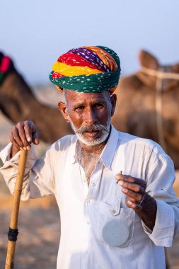 Pushkar, Rajasthan, India - November 10, 2024: Portrait of a rajasthani male in traditional clothes at desert fairground during the pushkar camel fair for trading camels.