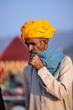 Pushkar, Rajasthan, India - November 10, 2024: Portrait of a rajasthani male in traditional clothes and colourful turban at desert fairground during the pushkar camel fair for trading camels.