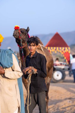 Pushkar, Rajasthan, India - November 10, 2024: Portrait of a rajasthani smoking male in traditional clothes at desert fairground during the pushkar camel fair for trading camels.