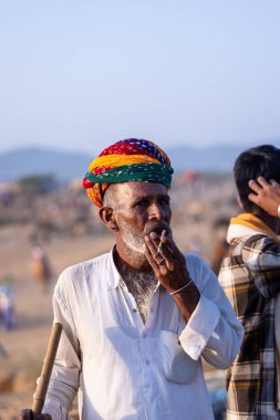 Pushkar, Rajasthan, India - November 10, 2024: Portrait of a rajasthani male in traditional clothes and colourful turban at desert fairground during the pushkar camel fair for trading camels.