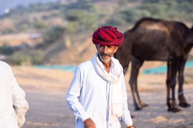 Pushkar, Rajasthan, India - November 10, 2024: Portrait of a rajasthani male in traditional clothes and colourful turban at desert fairground during the pushkar camel fair for trading camels.