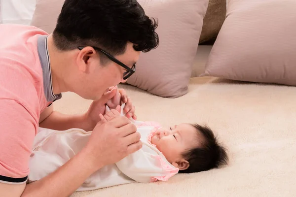 Asian father sing or talk with adorable daughter on bed, close up dad eye contact with healthy newborn 3 months with love and happy, toddler infant lie down on bed look to dad with curiosity.