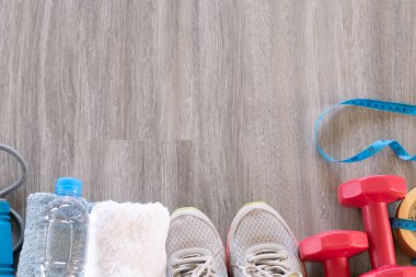 Spor aletleri, yaşam tarzı, fotokopi alanı konsepti, spor ayakkabısı, spor ayakkabısı, spor aletleri, spor aletleri, spor aletleri, halterler ve ahşap zeminde bir şişe saf su. 