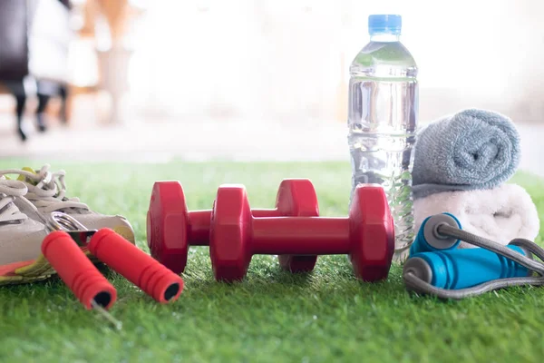 Gym stuff lifestyle exercise at home with copy space concept, sneaker exercise healthy lifestyle sport or athletes equipment, fitness accessories dumbbells, bottle of pure water on green grass indoor