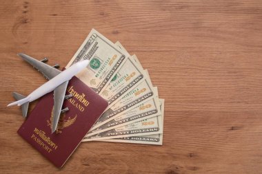 Tahta zemin üzerinde döviz ve uçak banknotları bulunan Tayland pasaportu, seyahat konsepti.