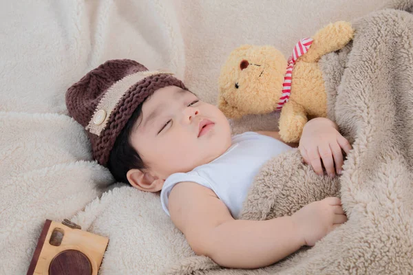 亚洲可爱的新生儿头戴褐色针织帽子 睡在玩具熊旁边 头戴米黄色毛毯 还带着安全舒适的玩具相机 小屁孩吃饱后很可爱的休息 — 图库照片