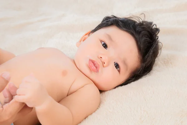 有选择地聚焦亚洲可爱的新生儿 年龄2 3个月 躺在床上 看着相机 牵着父亲的手指 可爱的婴儿躺在米黄色的床单上 凝视着镜头 看起来很平静 — 图库照片