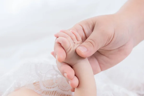 Mother\'s hand holds tiny newborn baby with soft tenderness, Closeup mother and daughter infant, toddler tiny finger hold mother for safety and trust