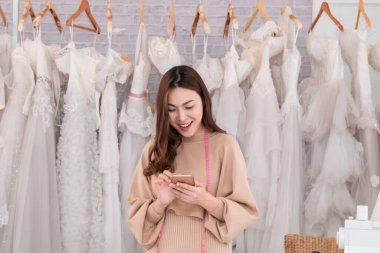 Seçici odaklanma Startup başarılı iş sahibi tasarımcı gelinliği. Sosyal ağdaki akıllı telefondan müşteriyle mobil iletişim kuran yaratıcı bir çalışan kadın. Kadın girişimci işi.