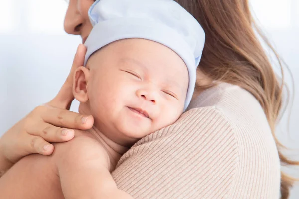 Selective focus of Beautiful Asian mother holding lovely newborn baby in arms with love and care. mom and adorable infant spend time together at home in holiday. Toddler happy trust safe with mom hug.
