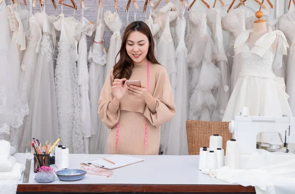 Selective focus Startup successful business owner designer wedding dress. Working woman creative using mobile communicating with client in social network smartphone. woman entrepreneur business.