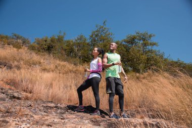 Atletizm çifti ormanda koşarken su içer, su içerek vücudunu tazeler. Afro-Amerikan erkek ve kadın koşucu spor eğitimi birlikte. Egzersiz ve sağlıklı yaşam tarzı.