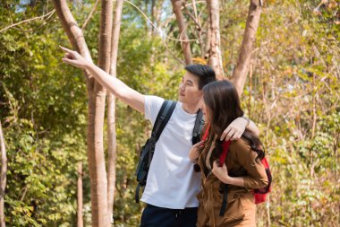 Young Asian couples have fun together in park, tourist outdoor adventure trip lifestyle spend time together trekking in forest during vacation or holiday, Adorable girl have happy time with boyfriend
