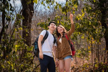 Young Asian couples have fun together in park, tourist outdoor adventure trip lifestyle spend time together trekking in forest during vacation or holiday, Adorable girl have happy time with boyfriend