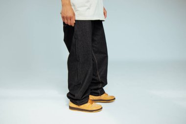 Bir erkek manken tarafından giyilen şık siyah kot tasarımına yakından bakıldığında, modern moda kavramlarında işçiliğin ve detaylara dikkat edilmesi.