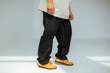 Bir erkek manken tarafından giyilen şık siyah kot tasarımına yakından bakıldığında, modern moda kavramlarında işçiliğin ve detaylara dikkat edilmesi.