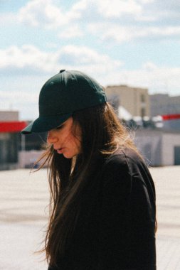 Yeşil şapkalı bir kadının profil görüntüsü. Işık, ince bulanıklık ve bulanıklık onun sakin duruşuna odaklanır, bir minimalist ama görsel olarak zorlayıcı bir görüntü yaratır..