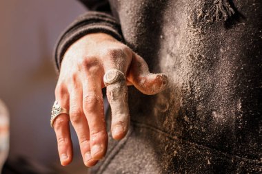 Ahşap işçisinin tozlu parmakları, süslü yüzüklerle süslenmiş, ahşap işçiliğindeki sanatsal ve işçiliğin karışımını gösteriyor..