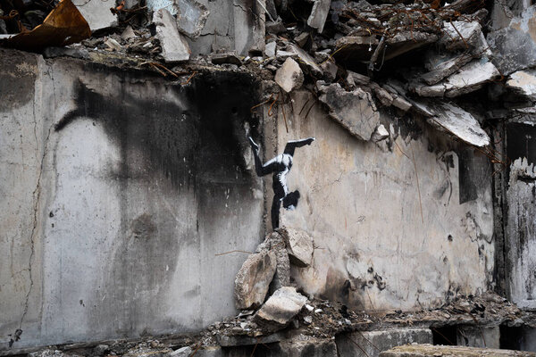 Borodyanka, Kyiv region 11.12.2022 The work of the mural of the British street artist Banksy on the wall of a destroyed house after the invasion of Russia in Ukraine. Gymnast girl stands on her hands
