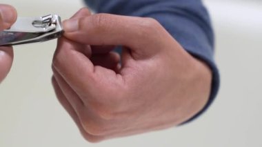 A guy cuts nails on fingers on his hand with pliers on a white background