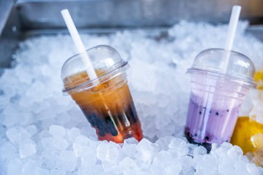 İki ferahlatıcı yaz içeceği - soğuk bir buzlu çay ve bir meyve suyu - ezilmiş buz yatağında sunulur, serin bir içecek seçeneği sunulur