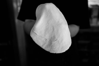 Bir şef taze pizza hamuru uzatır, monokrom detaylarıyla yakalanır..