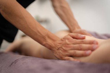 Bir masörün becerikli elleri, müşterinin bacağına derin doku masajı yaparak sakin bir spa ortamında kas sıkışmasından kurtulmasını sağlar..