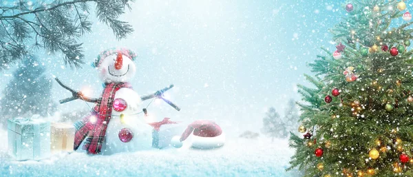 Happy snowman standing in winter christmas landscape.