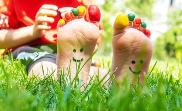 stock image Children's feet with a pattern of paints smile on the green grass. Selective focus. nature.