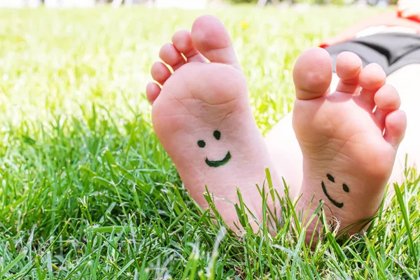 stock image Children's feet with a pattern of paints smile on the green grass. Selective focus. nature.