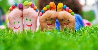 Yeşil çimlerin üzerinde gülümseyen boya desenli çocuk ayakları. Seçici odaklanma. Çocuk
