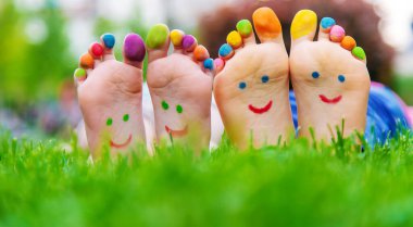 Yeşil çimlerin üzerinde gülümseyen boya desenli çocuk ayakları. Seçici odaklanma. Çocuk